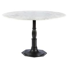 a white marble top dining table with black metal pedestals and an iron base, against a white background