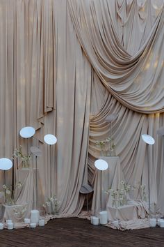 an image of a stage setting with drapes and flowers in vases on the floor