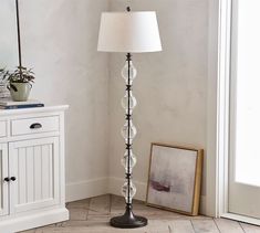 a lamp that is sitting on the floor next to a dresser and cabinet in a room