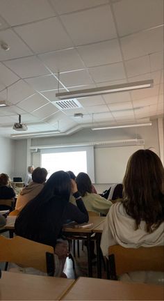 people are sitting at desks in a classroom with their backs turned to the camera