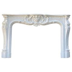 a white marble fireplace mantel with carvings