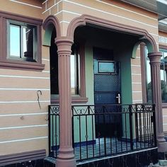 the front porch of a house with an iron fence and pillars on each side of it