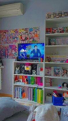 a bedroom with bookshelves full of comics on the wall and a television in the corner