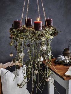 a chandelier with candles hanging from it's sides and greenery on the bottom