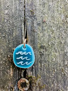 a blue glass ornament hanging on the side of a tree trunk with waves painted on it