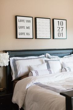 a bed with white linens and two framed pictures on the wall above it's headboard