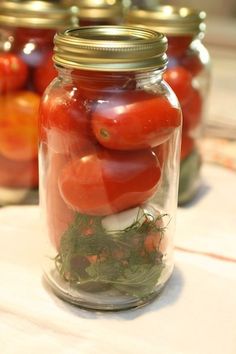 tomatoes and other vegetables in jars on a table