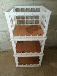 three tiered shelf with brown and white paint on the bottom, in front of a brick wall