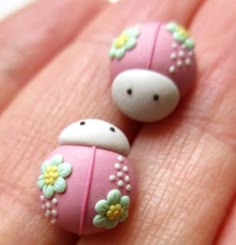 two tiny pink and white beads with flowers on them are held in someone's hand