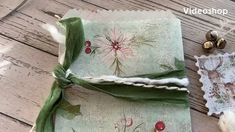 an old book is wrapped in green ribbon and decorated with holly berries, pine cones, and white cotton