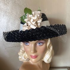 This Is A Beautiful And Elegant 1940s' Black Straw Wide Brim Hat. The Crown Is Flat At The Top And It Is Slanted, Per 1940's Fashions. The Crown Is Surrounded By An Upturned Wide Brim. There Is A Light Cream Colored Band Around The Crown, Plus A Veil That Is Attached So It Does Not Fall Over The Face. At The Front There Are Gorgeous Creme Colored Fabric Flowers + 2 Green Leaves. The Wartime 40’s Saw A Huge Variety Of Hats That Were Suitable For Any Face Shape, Hairstyle Or Personal Preference. Throughout The War & On Both Sides Of The Atlantic, Elaborate Creations Brightened Dreary Utility Fashions, Brought About By Rationing. The Only Items Not Rationed Were Hat Materials. Explosions Of Hat Cream, Colored Fabric, Creme Color, Cream Fabric, Color Bands, Light Cream, Flowers Leaves, Wide Brimmed Hats, Brim Hat