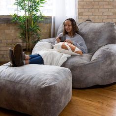 a woman sitting on a giant bean bag chair looking at her cell phone in the living room