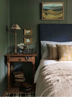 a bed sitting next to a wooden table with a lamp on it's side