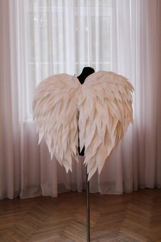 a mannequin made out of white feathers on a wooden floor in front of a window