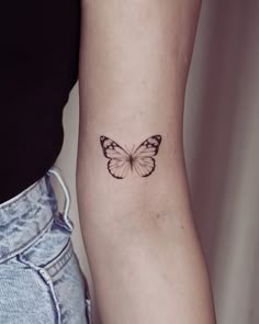 a woman's arm with a small butterfly tattoo on the left side of her right arm