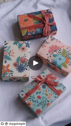 four wrapped gift boxes sitting on top of a white tablecloth covered bed next to each other