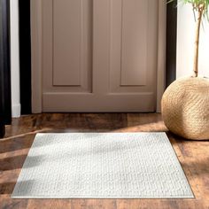 a white rug sitting on top of a hard wood floor next to a wooden door