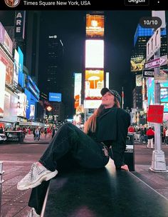 a woman sitting on top of a black table in the middle of a city at night