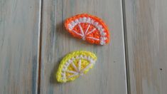 two crocheted lemons on a wood floor with one orange and the other yellow