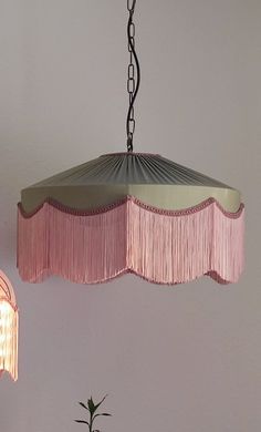 a pink chandelier hanging from the ceiling next to a potted plant on a table