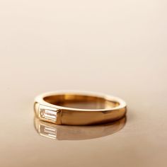 a yellow gold ring with two baguettes on the side, sitting on a white surface