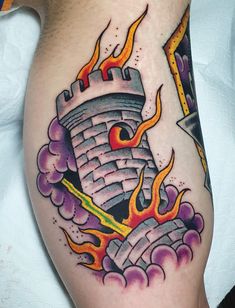 a man with a tattoo on his leg has a castle in the sky and flames coming out of it