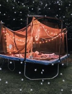 a tent with lights on it is in the middle of some grass and there are stars all around