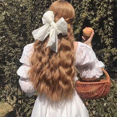 a woman with long red hair holding an apple in her hand and wearing a white dress