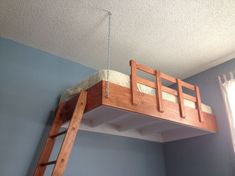 a wooden bunk bed suspended from the ceiling