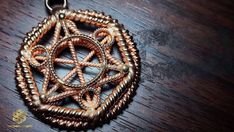 a brown and gold pendant with an intricate design in the center on a wooden table