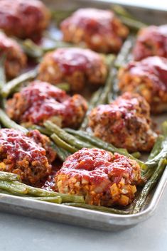 meatballs and green beans in a pan with ketchup on the top, ready to be eaten