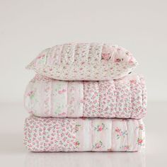 three blankets stacked on top of each other in pink and white floral print, with the covers folded down