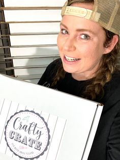 a woman wearing a hat holding up a box with the word crafty crate on it