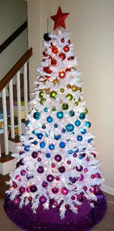 a white christmas tree decorated with multicolored ornaments