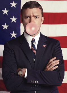 a man wearing a suit and tie with a bubble in front of an american flag