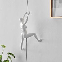 a white statue hanging from the side of a wall next to a potted plant