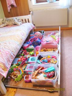 a drawer full of toys in a child's bedroom next to a bed and window