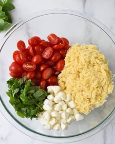 tomatoes, mozzarella and spinach in a glass bowl on a marble counter