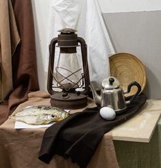 a table topped with a tea pot and a lamp next to a piece of paper