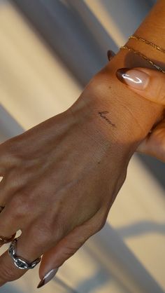 a woman's hand with two different rings on it and one has a small tattoo on her left wrist