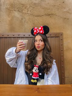 a woman in minnie mouse ears drinking from a cup