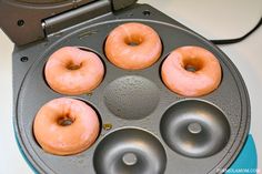 four donuts are being cooked in an electric waffle maker on a counter top