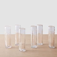 five clear vases sitting on top of a wooden table