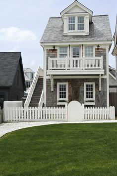 a large house with white picket fence and two story houses on the other side of it