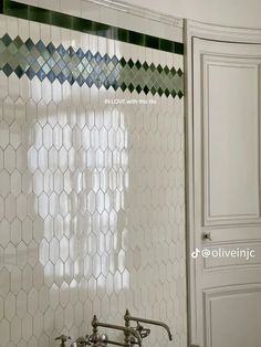 a bathroom with white and green tile on the walls