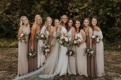 a group of women standing next to each other wearing dresses and holding bouquets in their hands