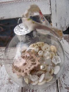 a glass bowl filled with buttons and seashells