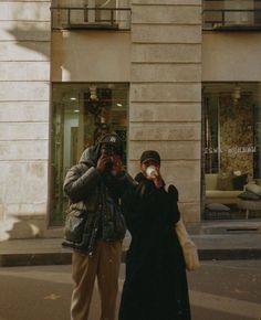 two people standing on the street taking pictures