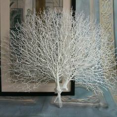 a white tree sitting on top of a table next to a mirror in a room