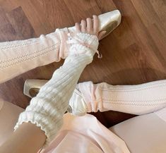 two women's legs in white socks and pink shoes on top of a wooden floor